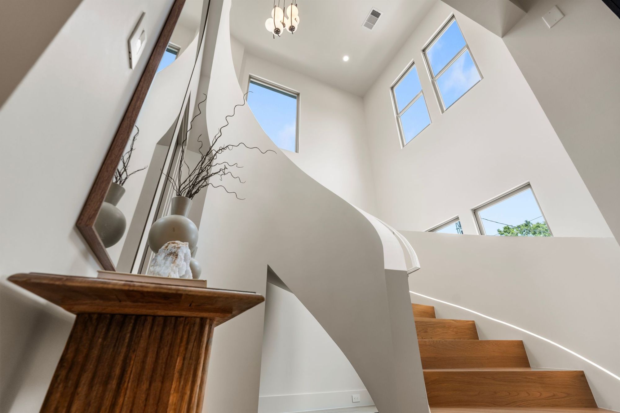 Sculptural curved staircase with white oak treads under clerestory windows